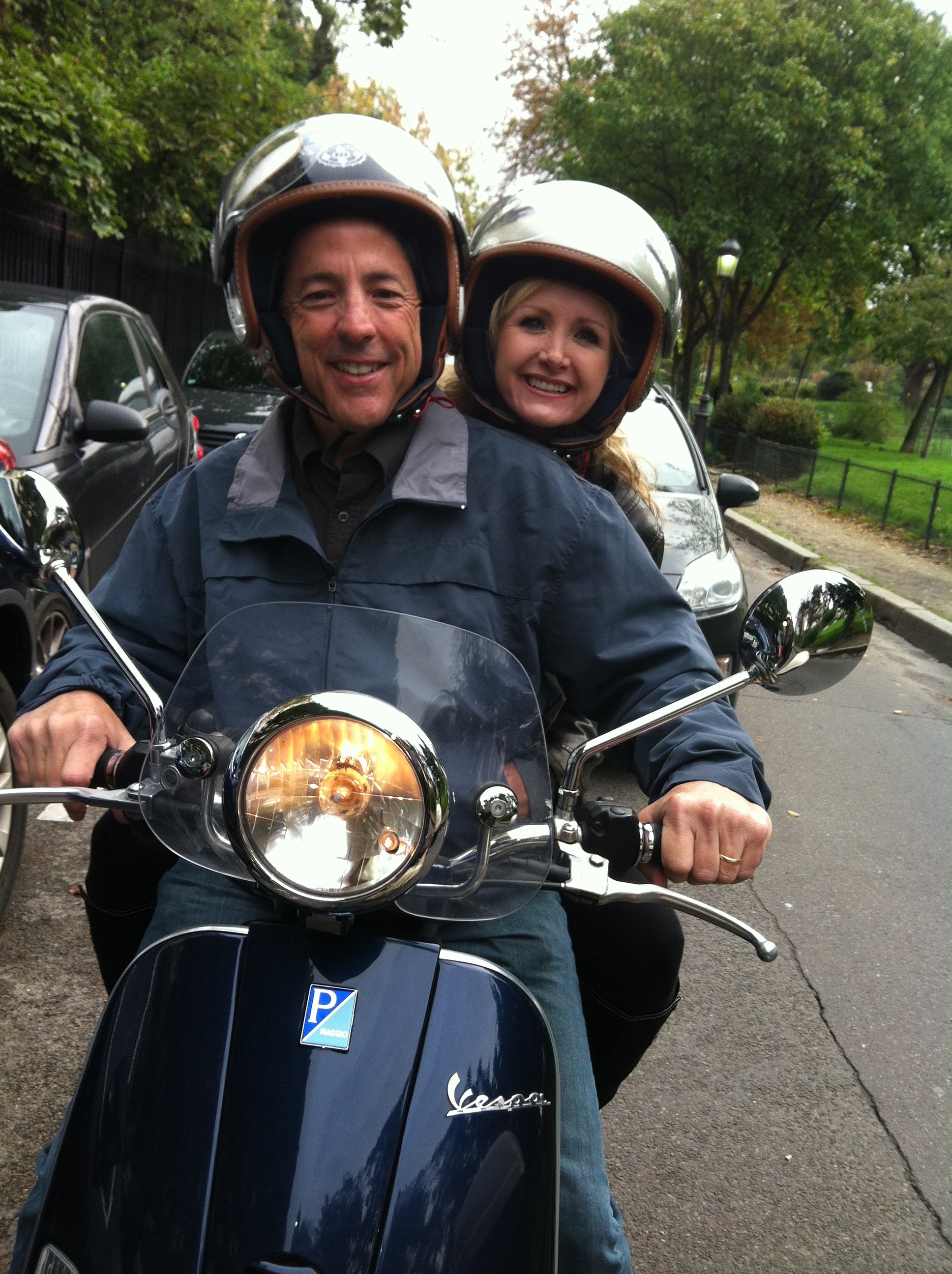Carrie & Boby at the wheel of a Vespa scooter in the street of Paris France during a Paris sightseeing Tour.